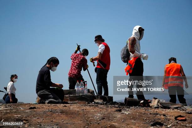 Residents remove debris from burned houses after a forest fire in the Poblacion Monte Sinai neighborhood in Viña Del Mar, Chile, on February 7, 2024....