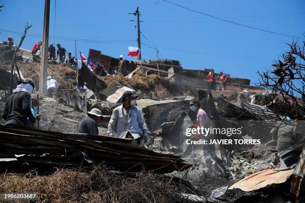 Residents remove debris from burned houses after a forest fire in the Poblacion Monte Sinai neighborhood in Viña Del Mar, Chile, on February 7, 2024....