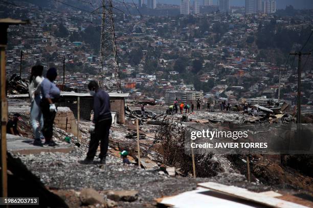 Residents remove debris from burned houses after a forest fire in the Poblacion Monte Sinai neighborhood in Viña Del Mar, Chile, on February 7, 2024....