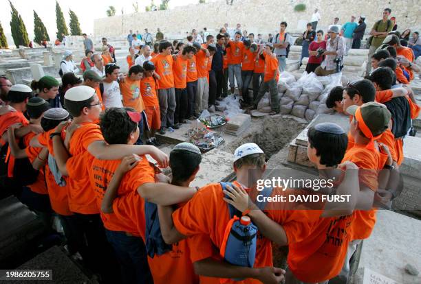 Wearing orange anti-disengagement T-shirts, friends of Avichai Levi from the southern West Bank Settlement of Beit Hagay, sing songs around his grave...