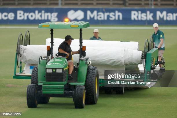 Ground staff place the covers over the pitch as rain delays the start of play before day three of the Sheffield Shield match between Victoria and...