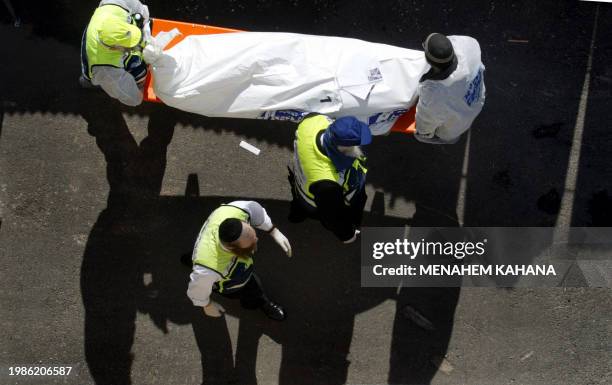 Jewish Ultra-Orthodox volunteers carry the a body one of 11 killed people killed following a Palestinian suicide attack in Jerusalem 29 January 2004....