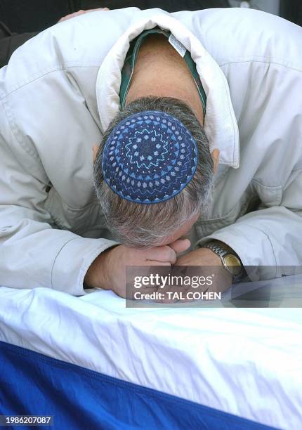 The father of Noam Leibowitz leans his head on the coffin of his son 26 December 2003 during his funeral at the West Bank settlement of Elqana some...