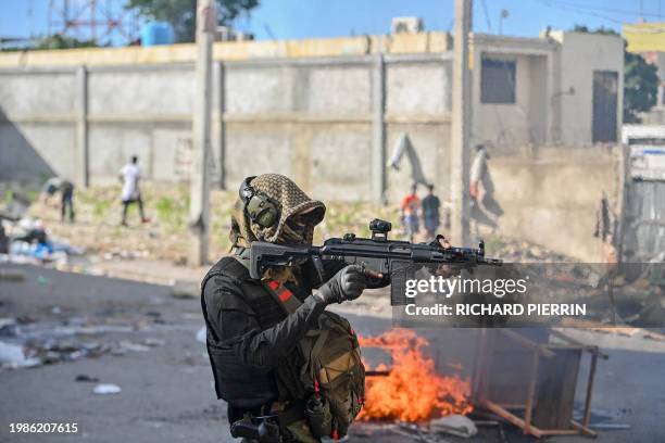 Policeman points a gun at protesters during a demonstration calling for the resignation of Prime Minister Ariel Henry in Port-au-Prince on February...