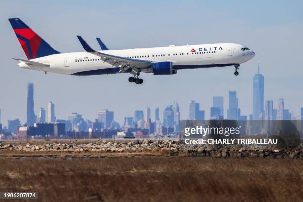 Boeing 767 passenger aircraft of Delta airlines arrives from Dublin at JFK International Airport in New York as the Manhattan skyline looms in the...