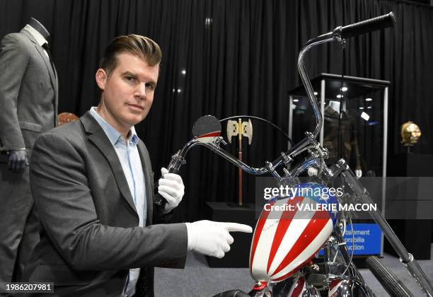 Brandon Alinger, Chief Operating Officer at Propstore, points to Peter Fonda's signature on the tank of the Harley Davidson Captain America panhead...