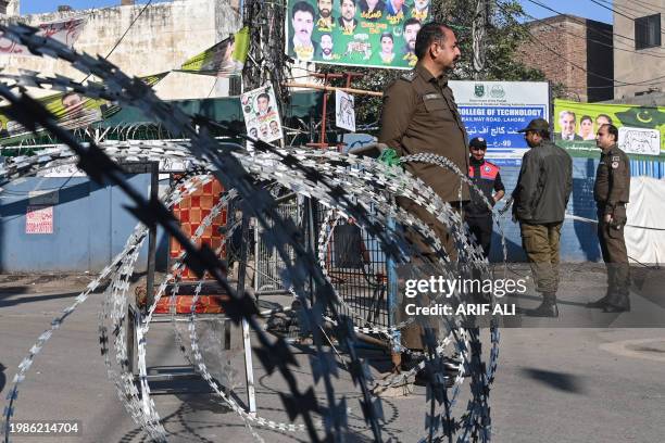 Policemen stand guard outside a polling station during Pakistan's national elections in Lahore on February 8, 2024. Millions of Pakistanis began...