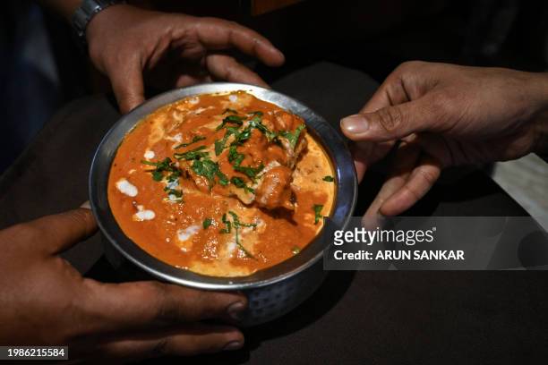In this photograph taken on January 29 a waiter serves butter chicken at the Moti Mahal restaurant in New Delhi. Butter chicken, one of India's most...