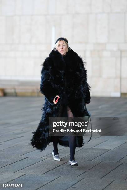 Guest wears a headband, a black fluffy long winter coat, tights, pointed shoes , outside OperaSport, during the Copenhagen Fashion Week AW24 on...