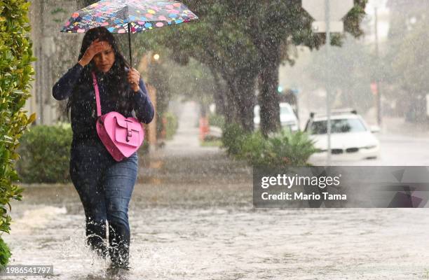 Person walks along a flooded street as a powerful long-duration atmospheric river storm, the second in less than a week, impacts California on...