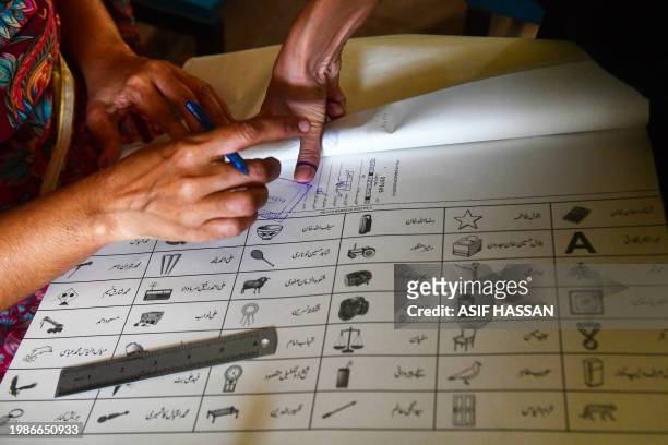 Woman presses her finger print on a ballot to vote at a poling station during Pakistan's national elections in Karachi on February 8, 2024. Pakistan...