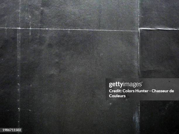 close-up of black posters stuck side by side on a wall. sunlight and shadows. natural colors. paris, france. - texture papier photos et images de collection