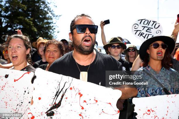 Protesters look on as government representatives are welcomed including New Zealand Prime Minister Christopher Luxon at Te Whare Rūnanga during a...