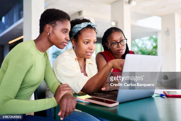 female student friends sitting at university campus, using laptop to work on a school project together. - black lives matter children stock pictures, royalty-free photos & images