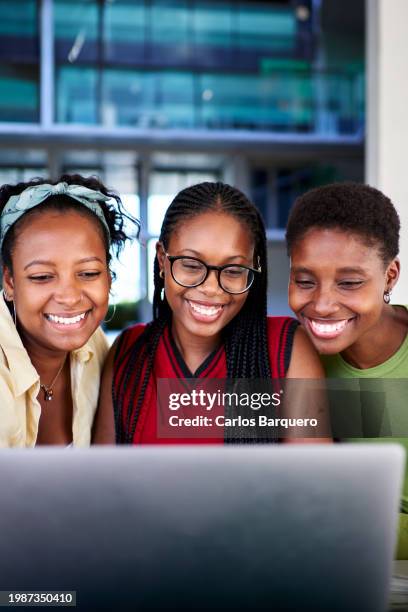 three african american student friends using a laptop to do homework together on the university campus, working on a school project. - black lives matter children stock pictures, royalty-free photos & images