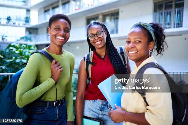 three african young women gathering together looking at camera smiling, standing at university hall. - black lives matter children stock pictures, royalty-free photos & images