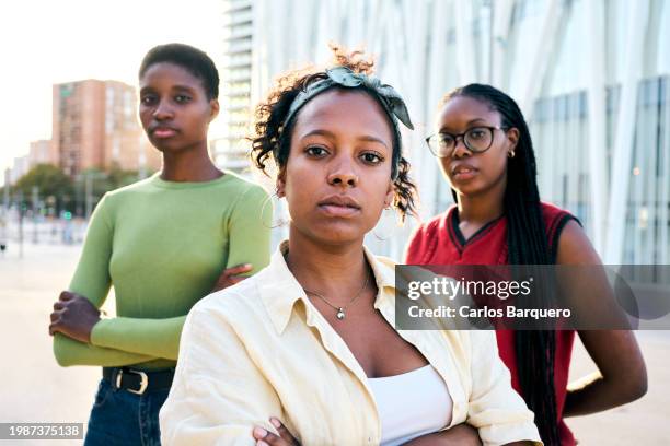 three young black women looking at camera seriously with arms crossed gesturing confidence. - black lives matter children stock pictures, royalty-free photos & images