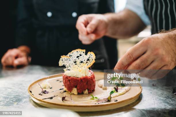 chefs are preparing a plate in the kitchen of the restaurant - chef perfection stock pictures, royalty-free photos & images