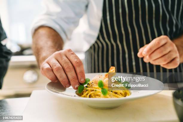 a chef is plating spaghetti - plating food hand stock pictures, royalty-free photos & images