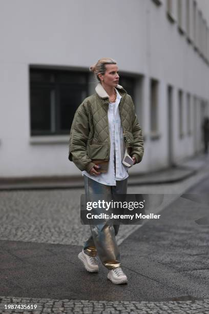 Jeanna Krichel seen wearing gold earrings and necklace, khaki green padded quilted jacket, white cotton blue flower pattern buttoned blouse shirt,...