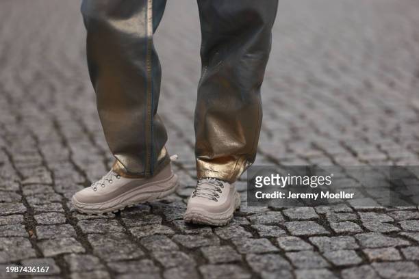 Jeanna Krichel seen wearing silver / gold metallic denim jeans / pants and Hoka Tor Summit oat milk / oxford tan sneakers, on January 26, 2024 in...