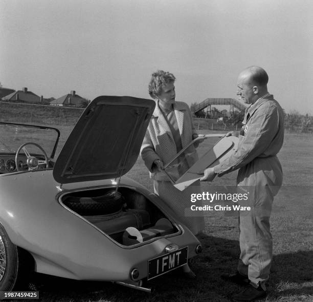 Car manufacturer Daphne Arnott and designer George Thornton taking a side windshield from the boot of the sports car they designed, London, November...