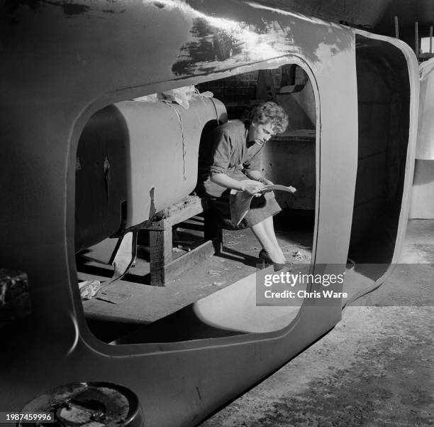 Car manufacturer Daphne Arnott sitting in the chassis of a sports car at Arnott's Garages in London, November 1955.