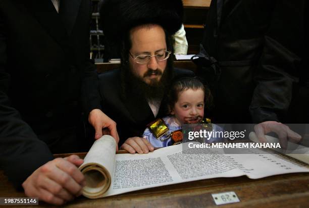 Child listens on as Ultra Orthodox Jews from the Wiznitz Hassidim group reads the Ester scrolls at the synagogue in the Israeli town of Beni Brak...