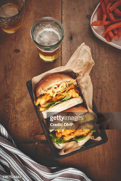 bier, burger und essen zum mitnehmen auf einem holztisch und fast food mit hühnchen und abendessen. glas, alkohol und abendessen mit einem korb oder grill mit luxus oder essen mit restaurant und köstlich zum abendessen - burger overhead stock-fotos und bilder