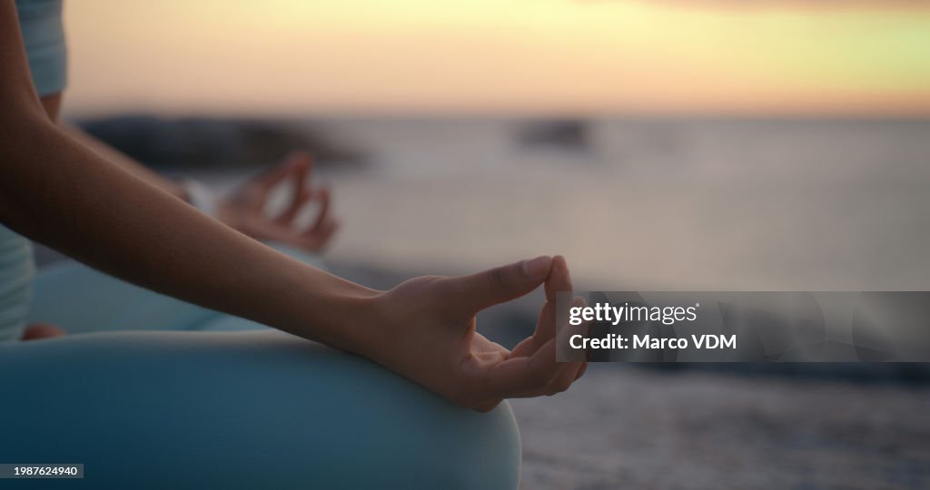 Person, hands and meditation on beach in sunset for spiritual wellness, inner peace or outdoor zen. Closeup of yogi in meditate, exercise or yoga for health, awareness or chakra by the ocean coast