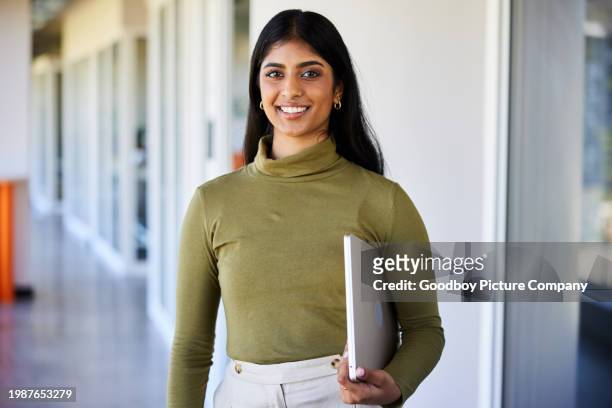 jeune femme d’affaires souriante avec un ordinateur portable debout dans le couloir d’un bureau - waist up photos et images de collection