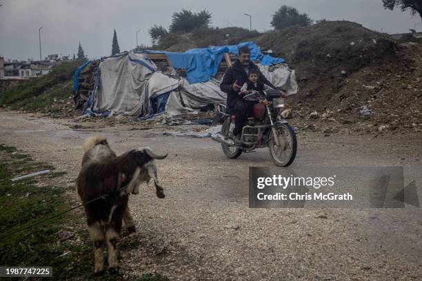 Adnan Dagli teaches his son Celal to ride his motorbike outside the families temporary container home after their house was destroyed in last years...