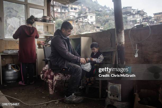 Adnan Dagli prepares chciken feed with his son Celal in front in the families temporary container home after their house was destroyed in last years...