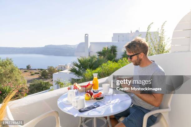 aegean delight: young man savors a scenic breakfast on a sunny terrace in his private villa - private terrace balcony stockfoto's en -beelden