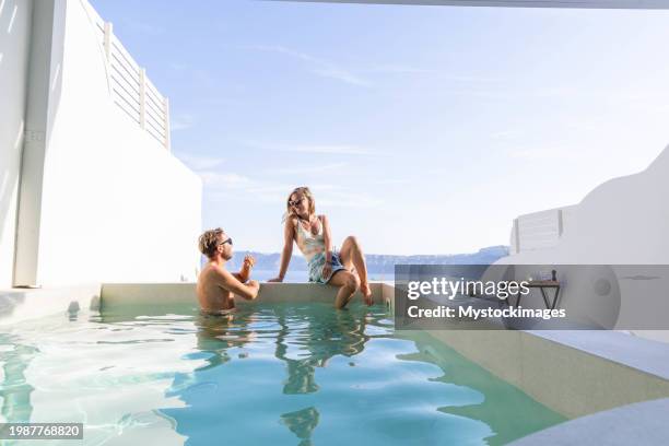 escapada griega: pareja joven relajándose en la piscina privada de la villa con vistas al mar - sólo con adultos fotografías e imágenes de stock