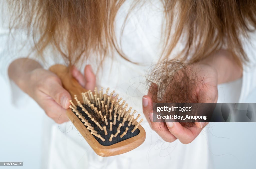 Cropped shot view of woman holding comb with hair loss after brushing her hair.