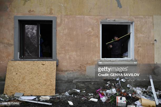 Local resident covers a broken window with a wooden plate following a missile attack in the town of Selydove, Donetsk region, on February 8 amid the...