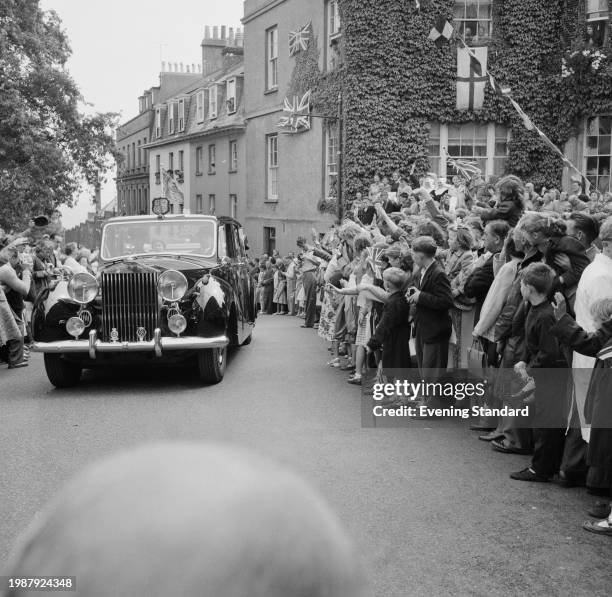 Queen Elizabeth II seated in a Rolls Royce drives past waving crowds during her Royal Tour of Guernsey, Channel Islands, July 26th 1957.