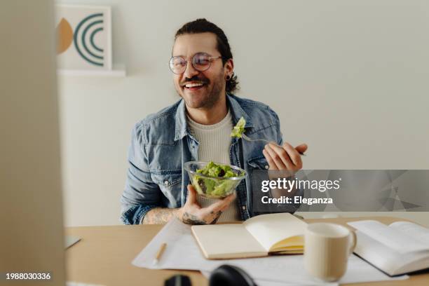 man using computer, learning, working and eating snack salad at home office - eating salad stock pictures, royalty-free photos & images