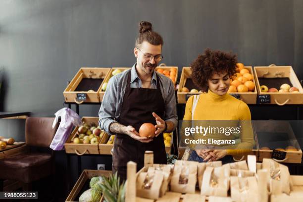 employee of a bio grocery shop helping a customer - apple products stock pictures, royalty-free photos & images