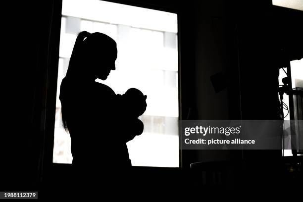 February 2024, Bremen: A woman stands with a newborn baby at the hospital window. Bremen wants to improve working conditions for nurses and midwives...