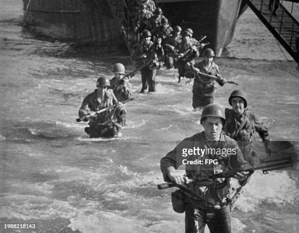American troops walking in the water leaving a landing barge during the Normandy D-Day landings, France, 6th June 1944.