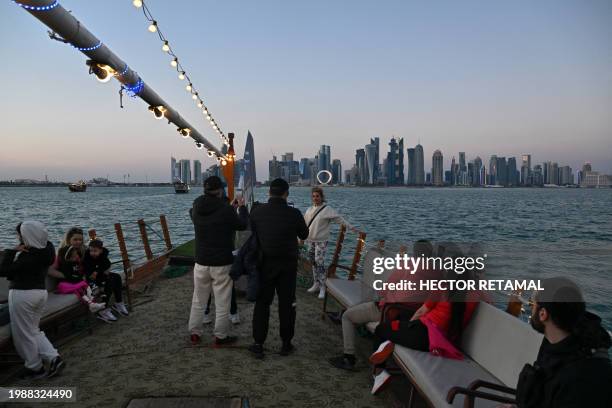 People cruise on a traditional Qatari dhow as skyscrapers of the West Bay are seen in the background in Doha on February 8, 2024.