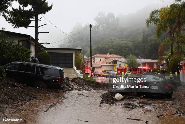 Firefighters gather near a mudslide as a powerful long-duration atmospheric river storm, the second in less than a week, continues to impact Southern...