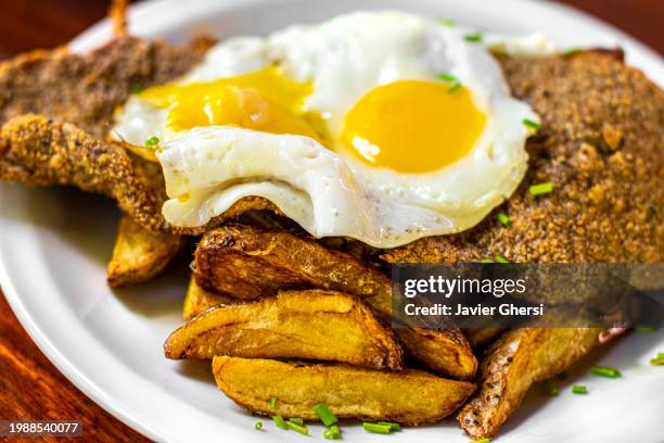 meat milanese with french fries and fried eggs on horseback - milanese 個照片及圖片檔