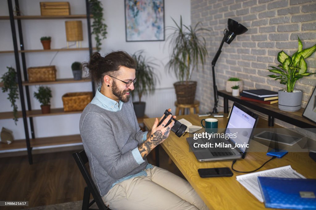 Young man photographer looking at images on camera while working in studio