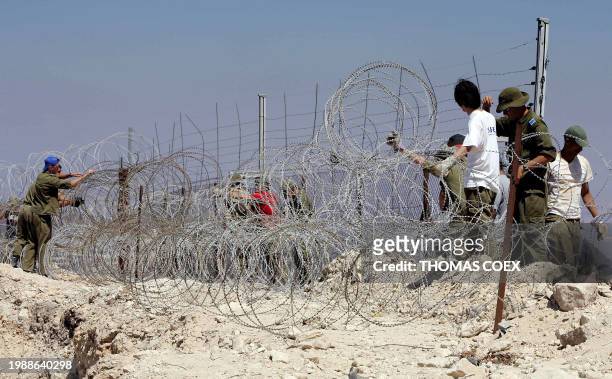 Israeli soldiers fix a new part of a barbed wire fence at the Israel-Lebanon border near the southern Lebanese town of Hula, 12 September 2006....