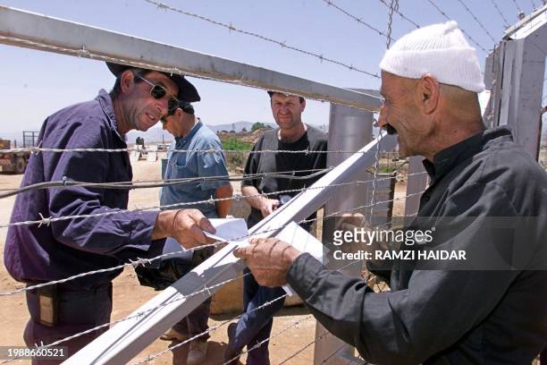 Druze receives his last salary from his Israeli employer through the barbed wire fence of the border between Israel and Lebanon 29 May 2000 at...