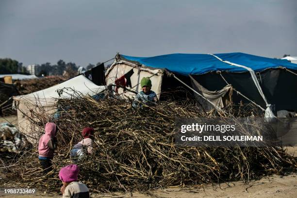 Displaced Syrian children play in a pile of wood twigs used for cooking, at the Al-Younani camp on the outskirts of the northern city of Raqa, amid a...