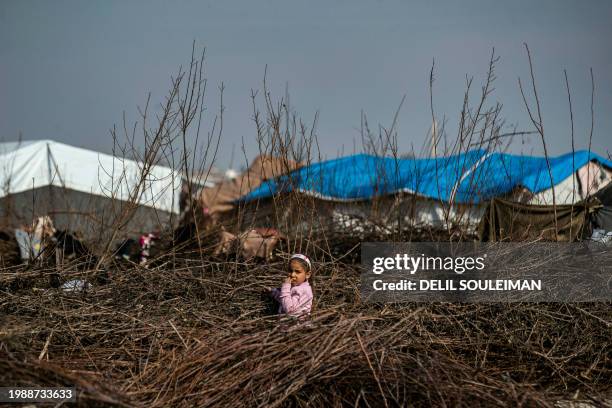 Displaced Syrian child stands in a pile of wood twigs used for cooking, at the Al-Younani camp on the outskirts of the northern city of Raqa, amid a...